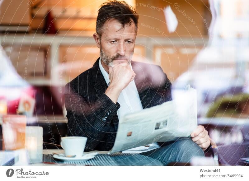 Porträt eines nachdenklichen reifen Geschäftsmannes, der in einem Café Zeitung liest Zeitungen lesen Lektüre Businessmann Businessmänner Geschäftsmänner Cafe