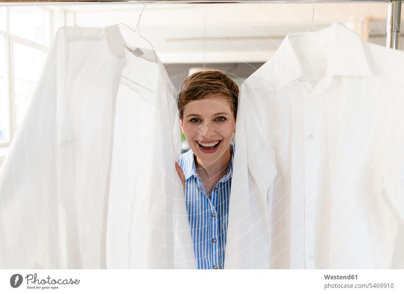 Porträt einer glücklichen Geschäftsfrau zwischen zwei weißen Hemden geschäftlich Geschäftsleben Geschäftswelt Geschäftsperson Geschäftspersonen Businessfrau