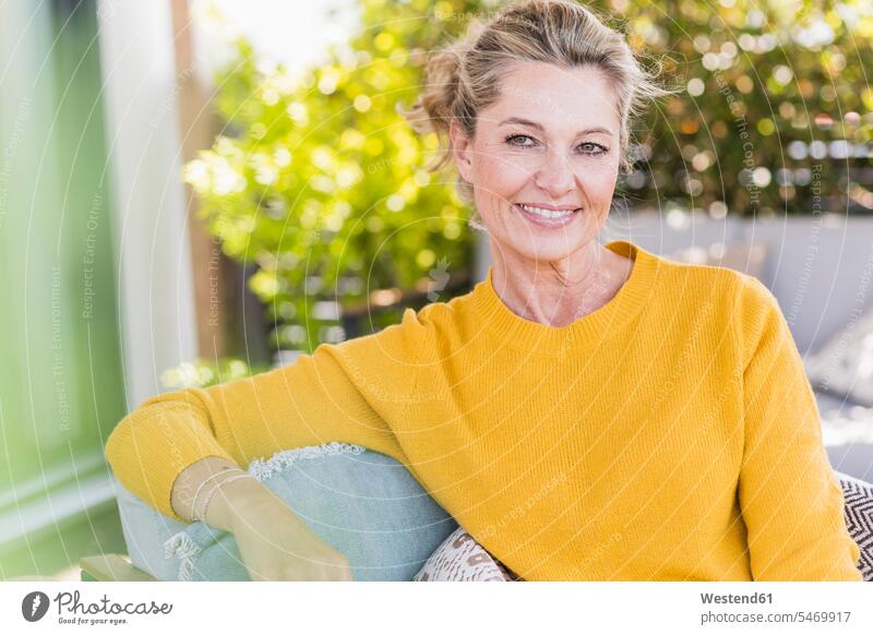 Porträt einer lächelnden reifen Frau, die auf der Terrasse sitzt Stuehle Stühle entspannen relaxen sitzend entspanntheit relaxt freuen geniessen Genuss Glück