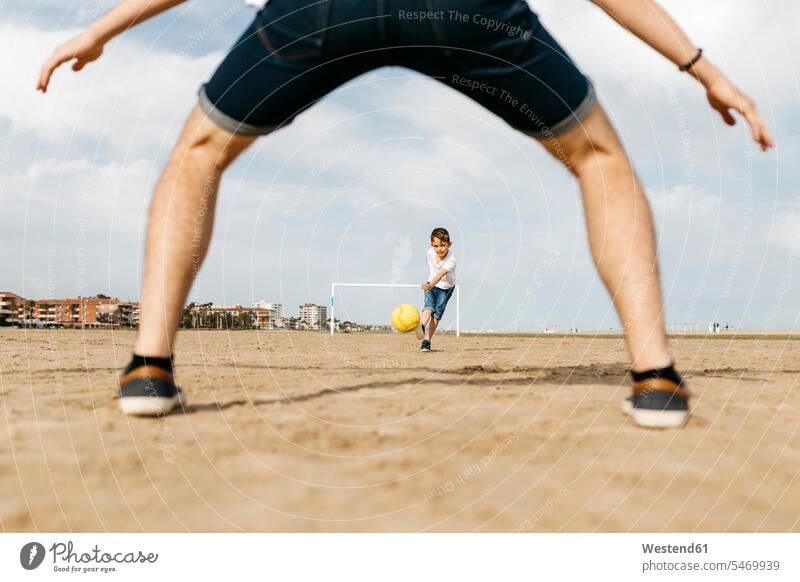 Mann und Junge spielen Fussball am Strand Leute Menschen People Person Personen Beine Bälle Fußbälle sommerlich Sommerzeit freuen Dynamik dynamisch Power Muße