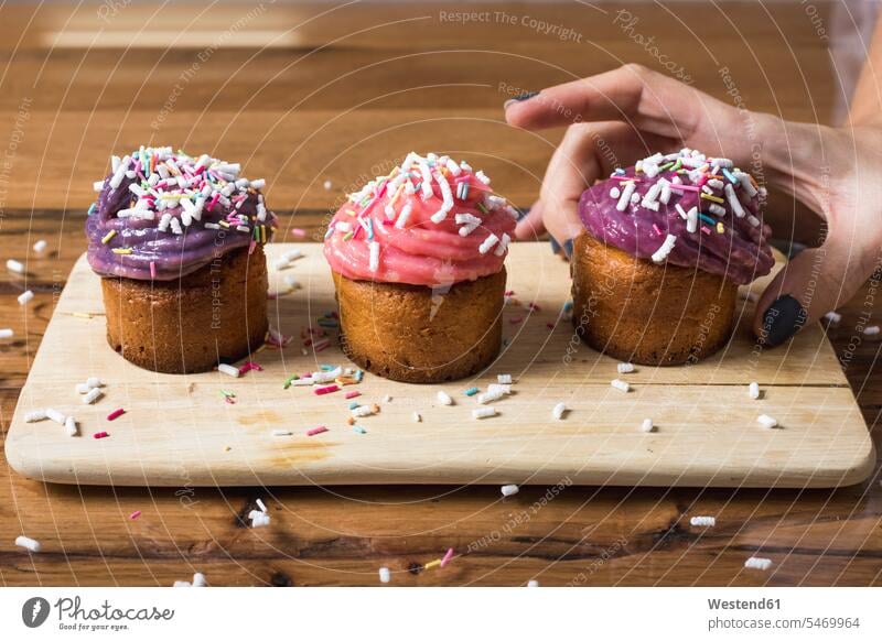 Frau nimmt Muffin Cupcake Cup Cake Cupcakess Cup Cakes Garnierung garnieren belegen garniert Belag Gebäck Backware Gebaeck Backwaren Süßspeise Süsses Süßes süß