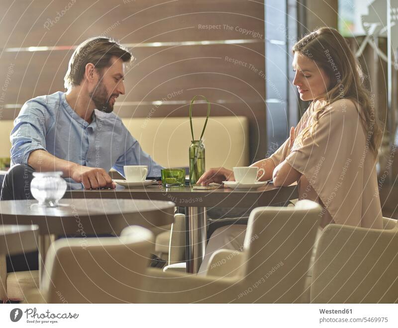 Mann und Frau sitzen am Tisch und trinken Kaffee Tische Kollegen Arbeitskollegen sitzend sitzt Getränk Getraenk Getränke Getraenke Food and Drink Lebensmittel