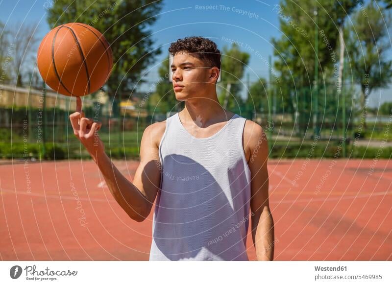 Junger Mann spielt mit Basketball gemischtrassige Person Nur ein junger Mann 1 1 junger Mann Basketbaelle Basketbälle Basketballspiel Bewegung sich bewegen