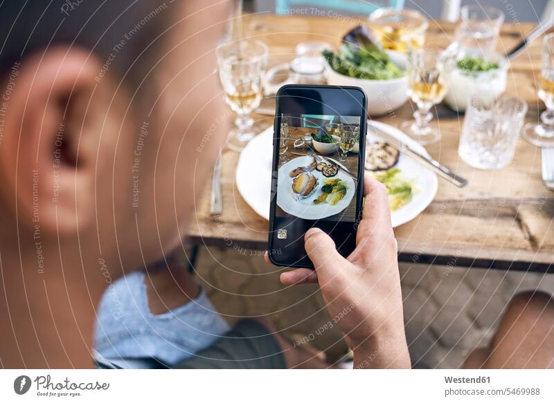 Mann, der ein Foto vom Essen auf einer Grillparty macht fotografieren Smartphone iPhone Smartphones Fotos Barbecue Grillparties Grillfest Grillen Grillfeste