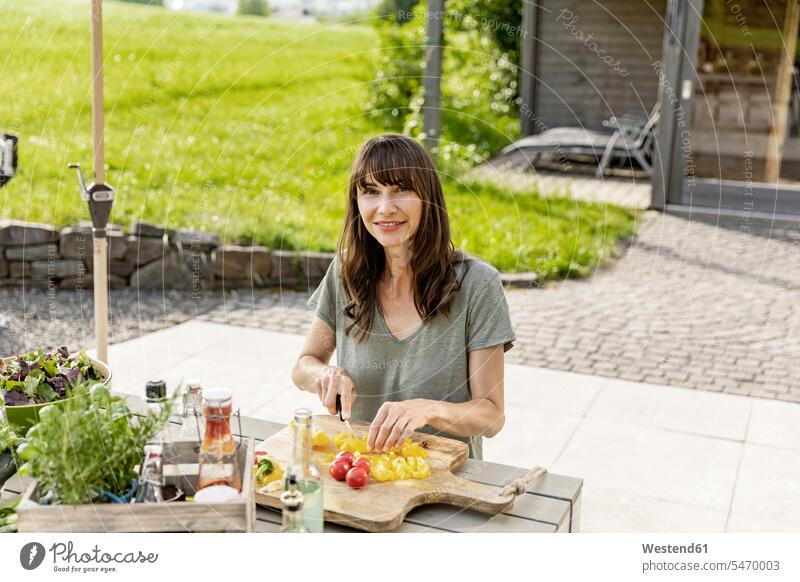 Porträt einer lächelnden Frau, die einen Salat auf einem Gartentisch zubereitet Leute Menschen People Person Personen Europäisch Kaukasier kaukasisch 1 Ein
