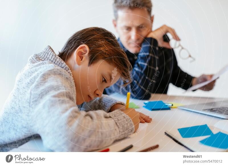 Geschäftsmann am Schreibtisch im Büro und betrachtet die Zeichnung seines Sohnes sitzen sitzend sitzt ansehen zeichnen Office Büros Arbeitstisch Schreibtische