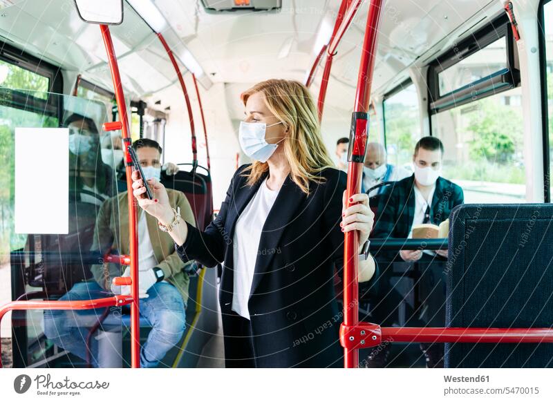 Geschäftsfrau mit Schutzmaske im öffentlichen Bus beim Blick auf Handy, Spanien Leute Menschen People Person Personen Europäisch Kaukasier kaukasisch