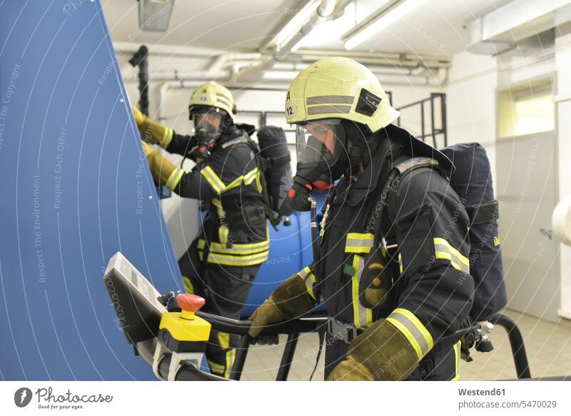 Zwei Feuerwehrmänner mit Atemschutzgerät und Drucklufttank bei einer Übung im Übungsraum Trainingsraum Feuerwehrmann Feuerwehrmaenner Feuerwehrleute
