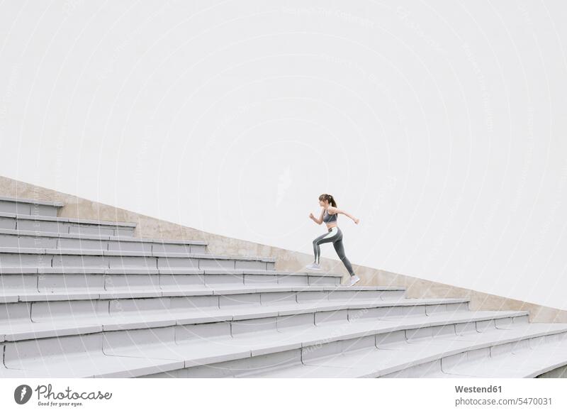 Junge Frau läuft auf Beton Tribüne rennen graue grauer graues Muße fit gesund Gesundheit Jogging Anreiz Ansporn Antrieb motivieren motiviert trainieren
