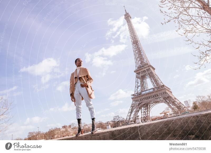 Nachdenkliche junge Frau steht auf Stützmauer mit Eiffelturm im Hintergrund, Paris, Frankreich Farbaufnahme Farbe Farbfoto Farbphoto Außenaufnahme außen draußen