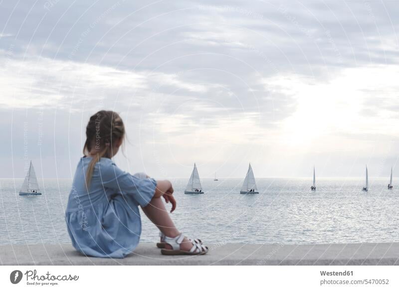 Kleines Mädchen schaut mit Booten aufs Meer Wasserfahrzeug Segelboote Segelschiff entspannen relaxen sitzend sitzt abends Jahreszeiten sommerlich Sommerzeit