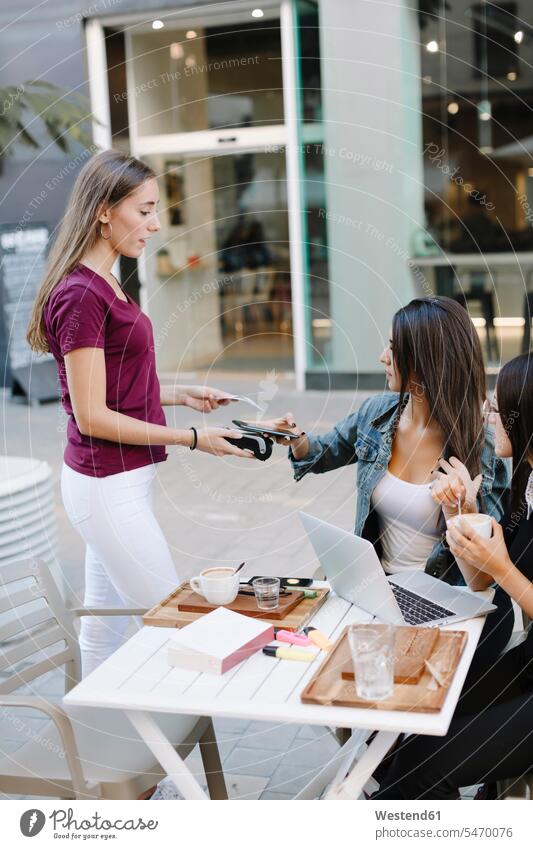 Junge Frau zahlt bargeldlos mit Smartphone in einem Café Textfreiraum Effizienz effizient Nützlichkeit Nutzen nützlich Kartenlesegerät Kartenlesegeraet Komfort