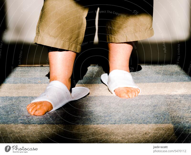 Haltlose Schlappen Hausschuhe Schuhe Fuß unbegründet Unpassend Beine Wärme Sonnenlicht feminin Teppich haltlos Detailaufnahme stehen zu Hause Latschen Füße weiß