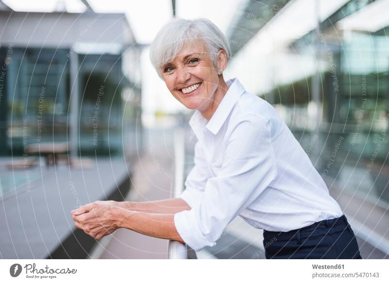 Porträt einer glücklichen älteren Frau, die sich auf ein Geländer in der Stadt stützt Glück glücklich sein glücklichsein Seniorin Seniorinnen alt aufstützen