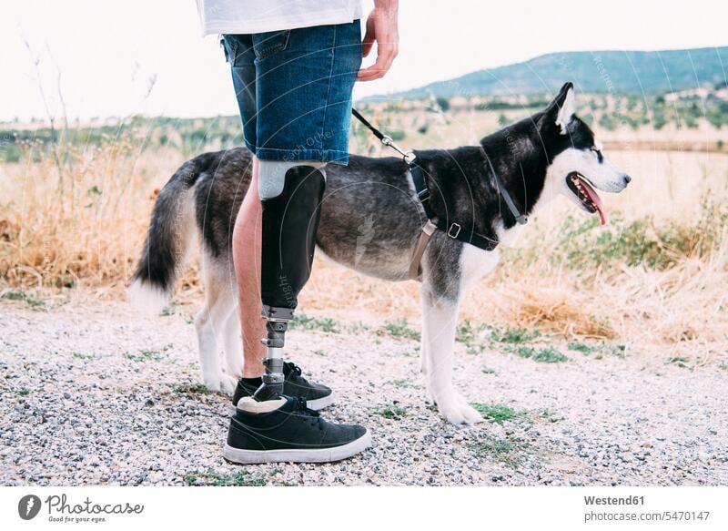 Junger Mann mit Beinprothese mit Hund auf Feldweg Leute Menschen People Person Personen Europäisch Kaukasier kaukasisch 1 Ein ein Mensch eine nur eine Person