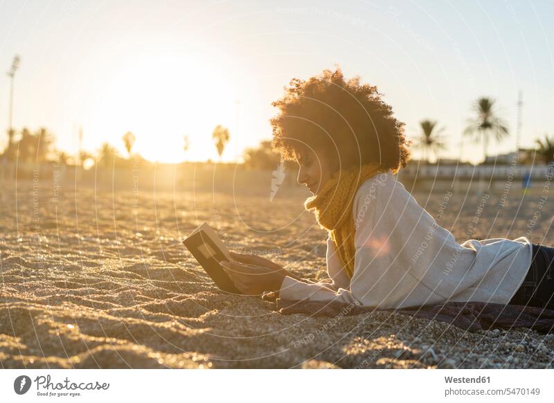 Frau, die im Sand liegt, sich am Strand entspannt und ein Buch liest sandig Entspannung Entspannen relaxen entspannen Frau mittleren Alters