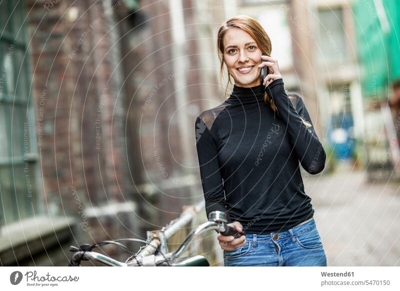 Porträt einer lächelnden Frau mit Fahrrad am Telefon weiblich Frauen Portrait Porträts Portraits Bikes Fahrräder Räder Rad telefonieren anrufen Anruf