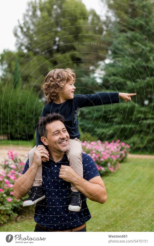 Glücklicher Vater trägt Sohn auf den Schultern im Park Parkanlagen Parks tragen transportieren glücklich glücklich sein glücklichsein Papas Väter Vati Vatis