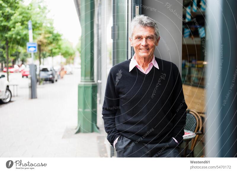 Porträt eines lächelnden älteren Geschäftsmannes, der vor einem Café steht geschäftlich Geschäftsleben Geschäftswelt Geschäftsperson Geschäftspersonen
