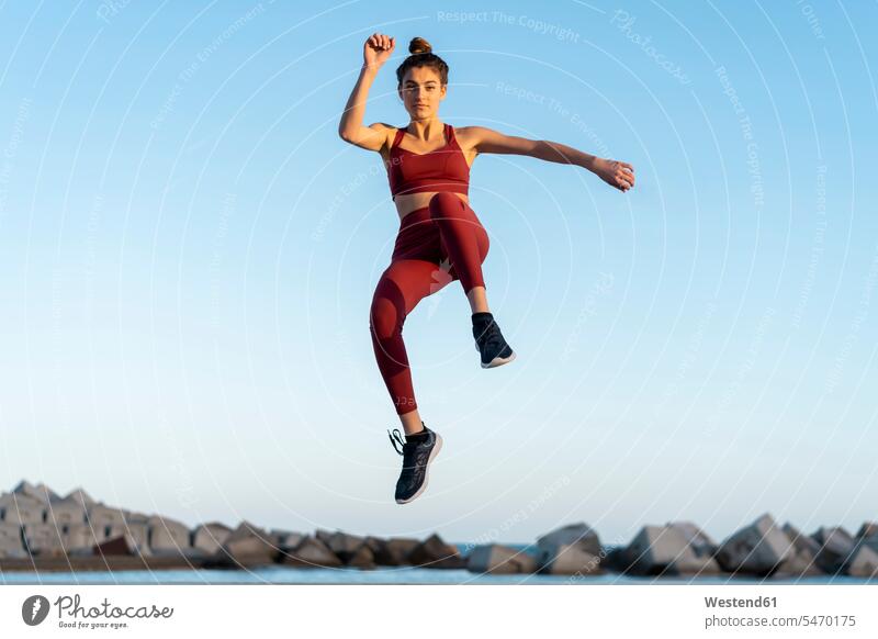 Sportliche junge Frau beim Workout, springend hüpfen in der Luft Sportlerin Sportlerinnen weiblich Frauen sportlich Dynamisch Dynamik Sprung Spruenge Sprünge