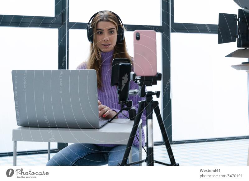 Porträt einer jungen Frau, die mit Laptop und Smartphone in einem Studio Aufnahmen macht Leute Menschen People Person Personen Europäisch Kaukasier kaukasisch 1