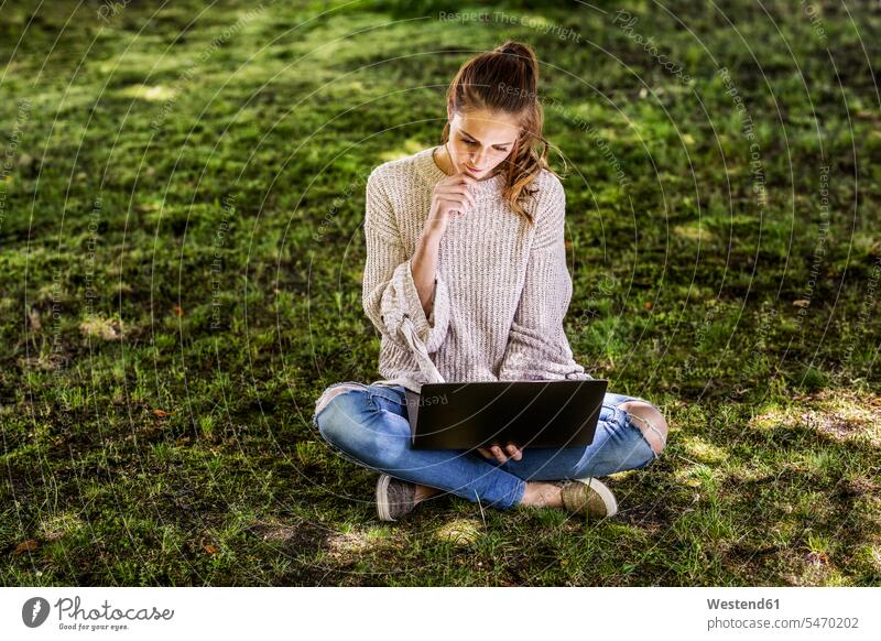 Nachdenkliche Frau sitzt mit Laptop auf einer Wiese Notebook Laptops Notebooks nachdenklich weiblich Frauen Wiesen benutzen benützen sitzen sitzend Computer