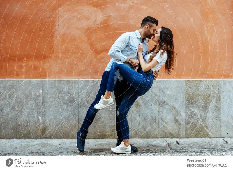 Verliebtes Liebespaar küsst sich vor einer Mauer im Freien Zuneigung verliebt lieben Paar Pärchen Paare Partnerschaft küssen Küsse Kuss Wand Wände Waende