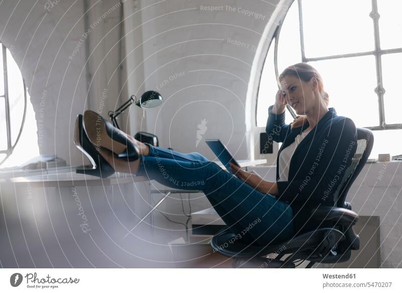 Geschäftsfrau mit Tablette mit Füßen auf dem Schreibtisch im Büro Geschäftsfrauen Businesswomen Businessfrauen Businesswoman Office Büros lächeln Arbeitstisch