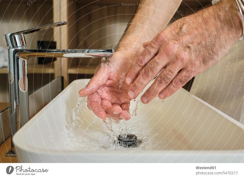 Reifer Mann wäscht Hände in fließendem Wasser im Badezimmer zu Hause Farbaufnahme Farbe Farbfoto Farbphoto Innenaufnahme Innenaufnahmen innen drinnen Spanien