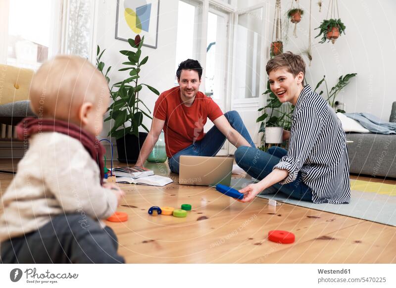 Glückliche Familie sitzt am Boden und spielt mit ihrer kleinen Tochter Zuhause zu Hause daheim spielen sitzen sitzend glücklich glücklich sein glücklichsein