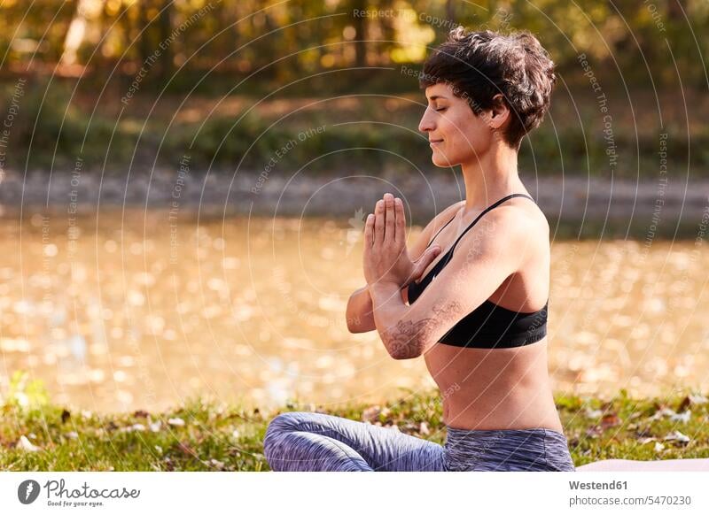 Mittlere erwachsene Frau am Flussufer beim Üben von Yoga, Meditation Yogini Yoginis Wald Forst Wälder meditieren Yoga-Übungen Yogauebungen Yogaübungen