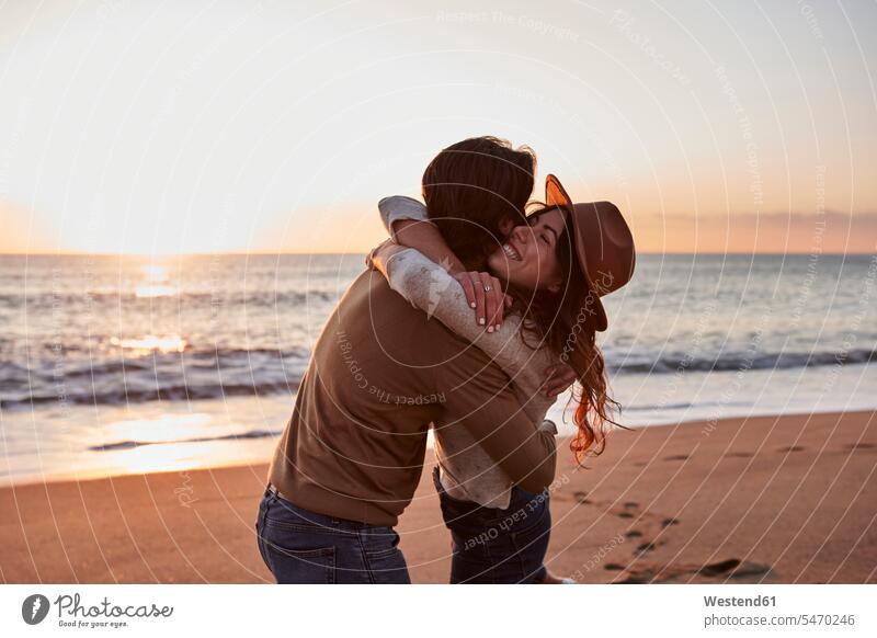 Junges Paar umarmt einander, während am Strand stehen Farbaufnahme Farbe Farbfoto Farbphoto Außenaufnahme außen draußen im Freien Freizeitkleidung