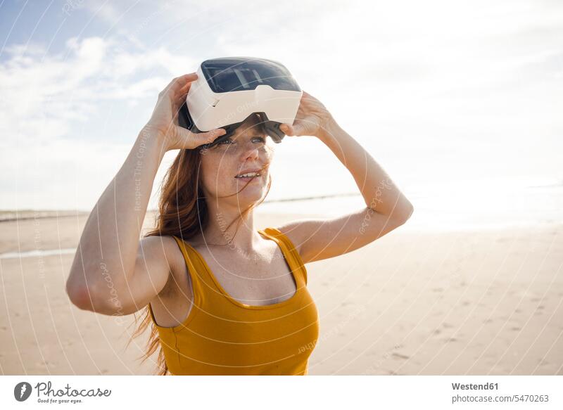 Rothaarige Frau mit VR-Brille am Strand Beach Straende Strände Beaches Virtual Reality Brille Virtual-Reality-Brille Virtual Reality-Brille VR Brille weiblich