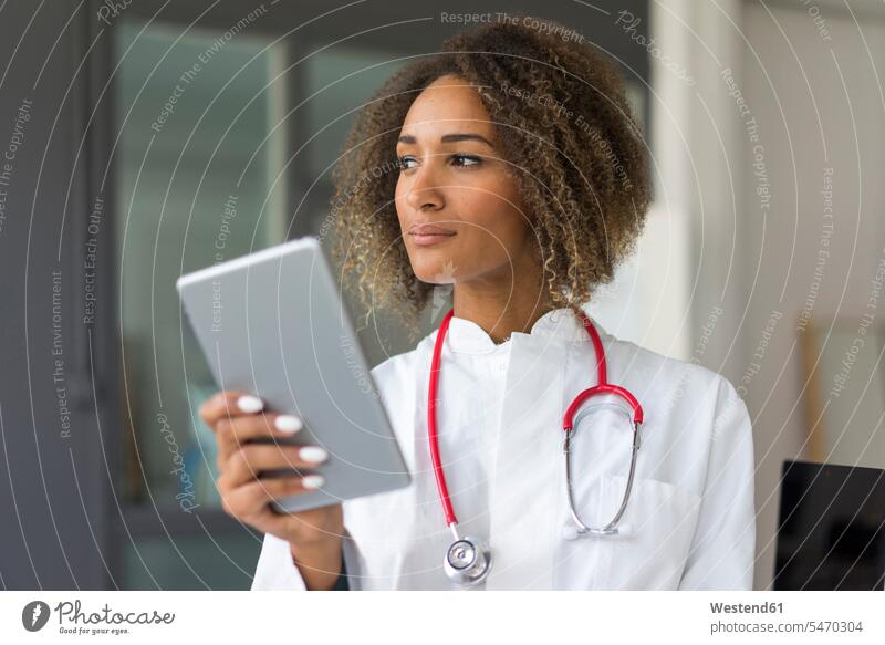 Porträt eines jungen Arztes mit Stethoskop und digitalem Tablett, der in die Ferne schaut Job Berufe Berufstätigkeit Beschäftigung Jobs Berufsbekleidung
