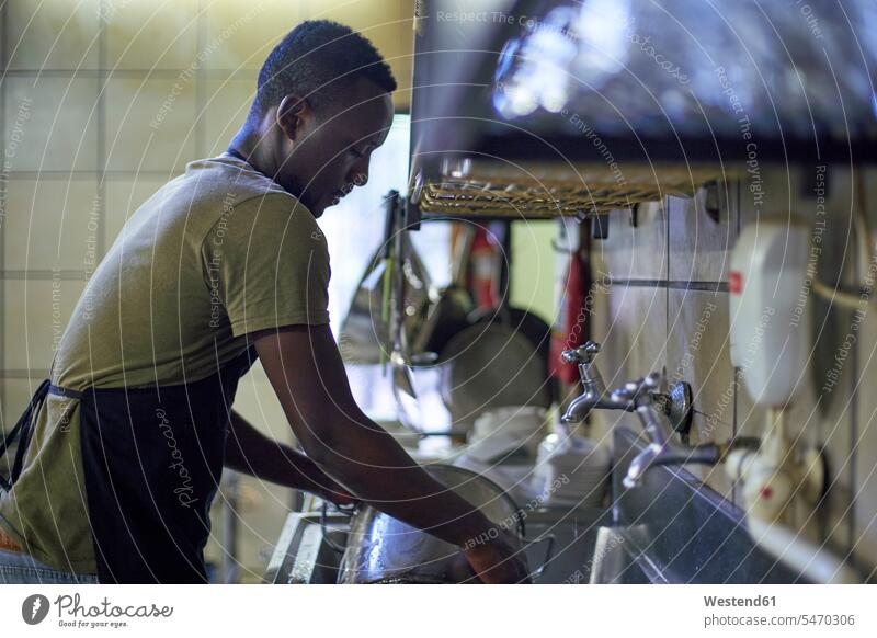 Junger Mann beim Geschirrspülen in der Restaurantküche, Südafrika Job Berufe Berufstätigkeit Beschäftigung Jobs Kochtoepfe Kochtöpfe Topf Töpfe Arbeit