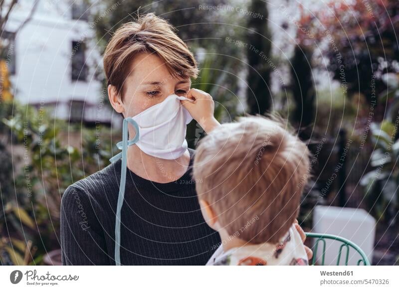 Kleiner Junge hilft seiner Mutter, eine Gesichtsmaske aufzusetzen Leute Menschen People Person Personen Europäisch Kaukasier kaukasisch 2 2 Menschen 2 Personen