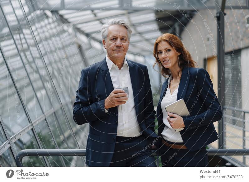Porträt eines selbstbewussten Geschäftsmannes und einer selbstbewussten Geschäftsfrau in einem modernen Bürogebäude Leute Menschen People Person Personen