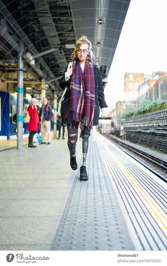 Junge Frau mit Beinprothese beim Gehen am Bahnsteig Leute Menschen People Person Personen Europäisch Kaukasier kaukasisch Nordeuropäisch 1 Ein ein Mensch eine