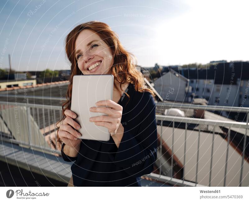 Glückliche rothaarige Frau mit Tablette auf der Dachterrasse Leute Menschen People Person Personen Europäisch Kaukasier kaukasisch 1 Ein ein Mensch eine
