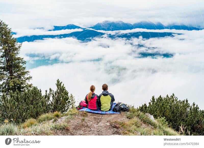 Junges Paar auf einer Wanderung in den Bergen bei einer Pause, Herzogstand, Bayern, Deutschland Touristen Decken Rucksäcke sitzend sitzt entspannen relaxen