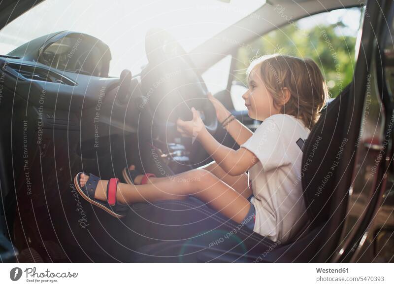 Glücklicher kleiner Junge sitzt auf dem Fahrersitz in einem Auto Fahrersitze glücklich glücklich sein glücklichsein Wagen PKWs Automobil Autos sitzen sitzend