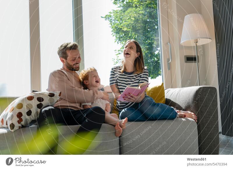 Fröhliche Familie genießt das Lesen von Märchenbüchern, während sie zu Hause auf dem Sofa sitzt Farbaufnahme Farbe Farbfoto Farbphoto Innenaufnahme