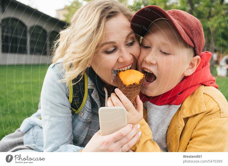 Mutter und Sohn essen gemeinsam Eiscreme Telekommunikation telefonieren Handies Handys Mobiltelefon Mobiltelefone sitzend sitzt freuen geniessen Genuss innig