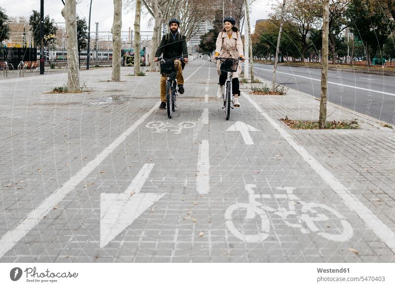 Pärchen fährt mit E-Bikes in der Stadt auf dem Fahrradweg staedtisch städtisch Radweg fahren eBikes Elektrofahrrad Elektrorad Paar Paare Partnerschaft radfahren