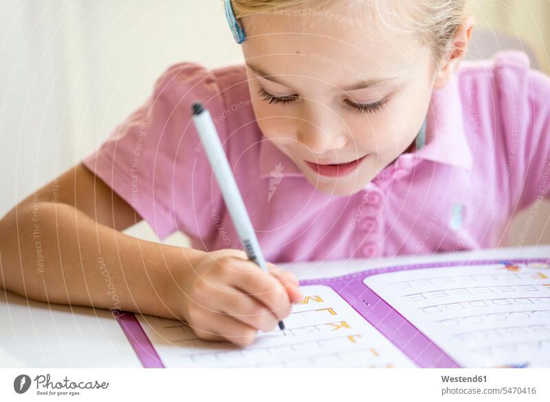 Lächelndes kleines Mädchen schreibt Alphabet schreiben aufschreiben notieren schreibend Schrift weiblich Kind Kinder Kids Mensch Menschen Leute People Personen