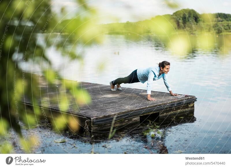 Frau macht Liegestütze auf einem Steg an einem See Liegestützen Push-Up Pushups Push-Ups Seen Stege Anlegestelle weiblich Frauen Muskeltraining Fitness fit