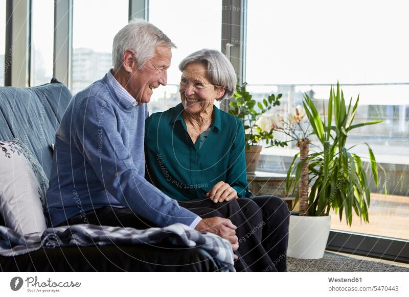 Lachendes älteres Paar sitzt zusammen auf der Couch Sofa Couches Liege Sofas sitzen sitzend lachen Seniorenpaar Seniorenpaare ältere Paare Seniorenpärchen