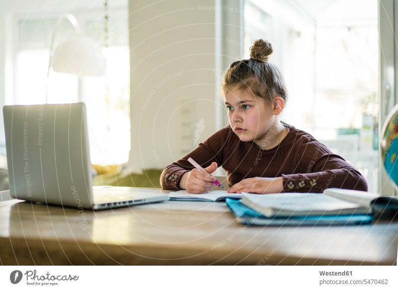Mädchen schreibt in Buch, während sie zu Hause am Laptop lernt Farbaufnahme Farbe Farbfoto Farbphoto Innenaufnahme Innenaufnahmen innen drinnen Tag