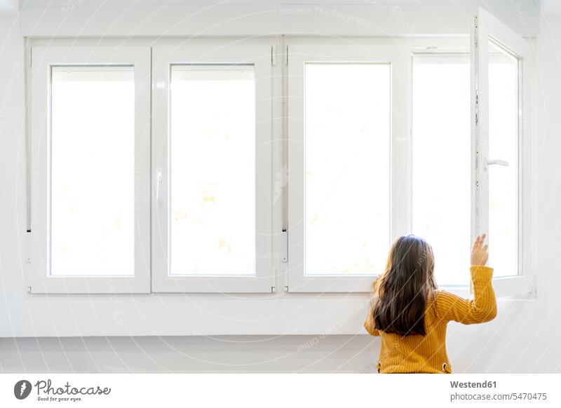 Mädchen öffnet Fenster und schaut hinaus, während sie zu Hause steht Farbaufnahme Farbe Farbfoto Farbphoto Innenaufnahme Innenaufnahmen innen drinnen Tag