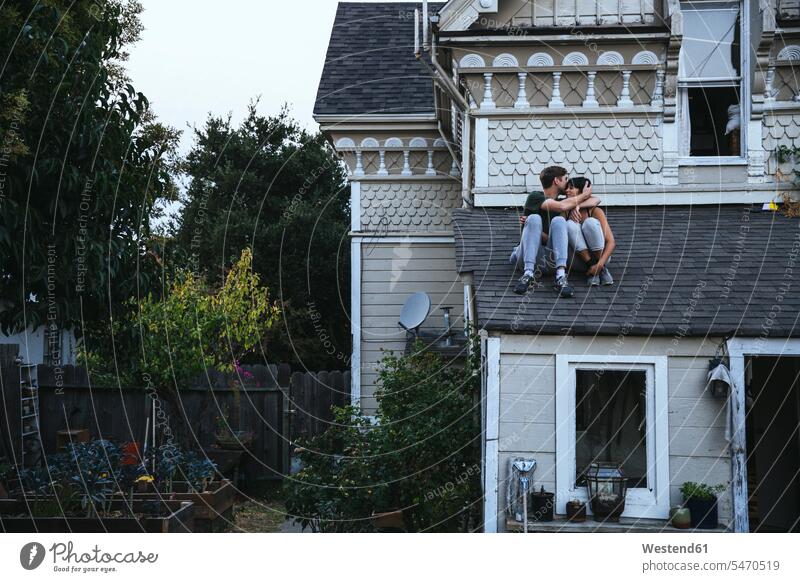 Auf dem Dach sitzendes Paar küsst sich sitzt küssen Küsse Kuss Pärchen Paare Partnerschaft Mensch Menschen Leute People Personen Entspannung relaxen entspannen